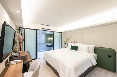 a bedroom with a bed and a desk and a television at Kaya Heritage Hotel in Bangkok