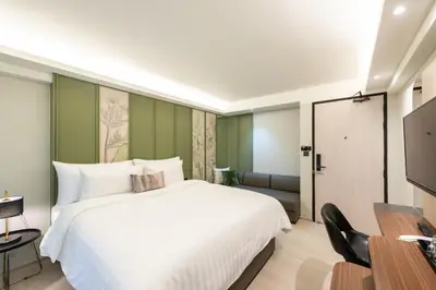 a bedroom with a white bed and a television at Kaya Heritage Hotel in Bangkok