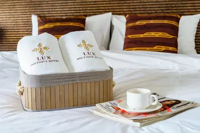 a bed with two towels and a cup of coffee at Lux Boutique Hotel in Nonthaburi