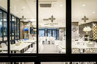 a dining room with white tables and white chairs at Lux Boutique Hotel in Nonthaburi