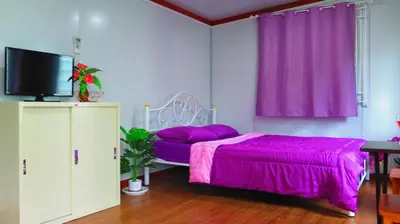 a bedroom with a purple bed and a tv at Pranot Apartment & Spa in Nonthaburi