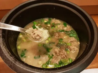 a bowl of soup with a spoon in it at Pranot Apartment & Spa in Nonthaburi