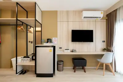 a room with a refrigerator and a desk with a tv at Amanah Bangkok Hotel in Bangkok