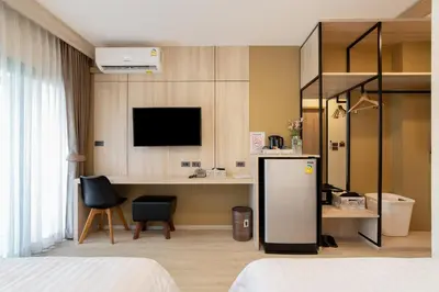 a hotel room with a desk and a refrigerator at Amanah Bangkok Hotel in Bangkok