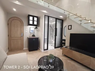 a living room with a flat screen tv and a staircase at Double Bed Hotel in Bangkok