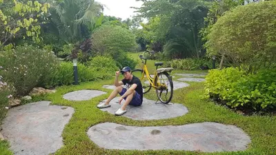a woman sitting on the ground next to a bike at BaanSuanklaiKlungBangkrachao บ้านสวนใกล้กรุงบางกะเจ้า in Phra Pradaeng
