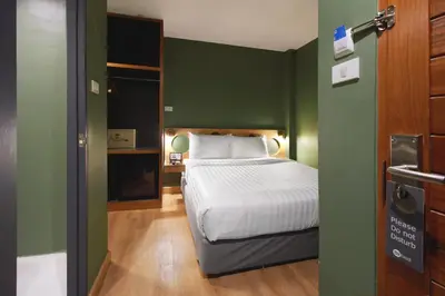 a bedroom with a bed and a green wall at MyBed Ratchada in Bangkok