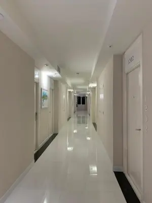 a hallway in a building with white walls and white floors at Icare Residence & Hotel in Bangkok