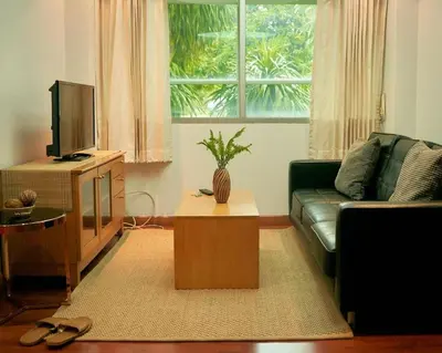 a living room with a couch and a tv at Bellevue Boutique Bangkok in Amphoe Phra Khanong