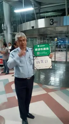 an older man is holding a sign in an airport at Airport Transfer Bangkok apartment in Thung Si Kan