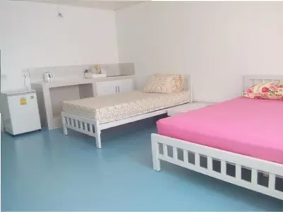 a room with two beds and a bench and a table at Thailand Taxiapartment Hostel in Thung Si Kan