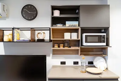 a desk with a microwave and a clock on a wall at My space69 in Ban Pak Khlong Khwang