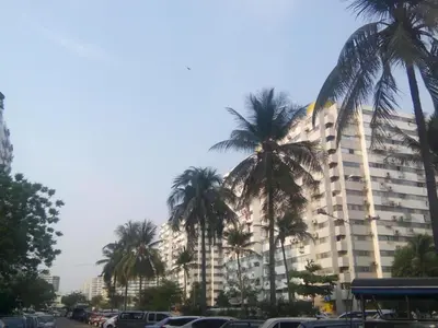 a large building with palm trees in front of it at Asia Don Mueang Bangkok Condominium in Thung Si Kan