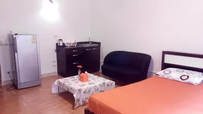 a room with a chair a desk and a refrigerator at Asia Don Mueang Bangkok Condominium in Thung Si Kan