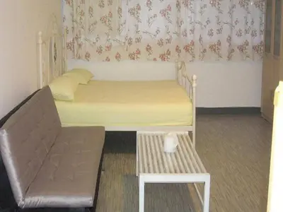 a small bedroom with a bed and a chair at Impact Don Mueang Bangkok Guest House in Thung Si Kan
