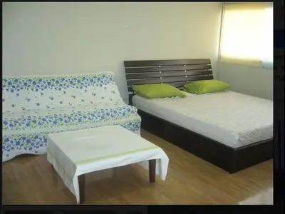 a bedroom with two beds and a bench and a table at Impact Don Mueang Bangkok Guest House in Thung Si Kan