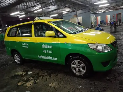 a small green and yellow car parked in a garage at Impact Thunder Dome Service Taxi in Thung Si Kan