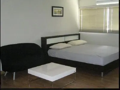 a bedroom with a bed and a chair and a table at Thailand Taxi Apartment Hostel in Thung Si Kan