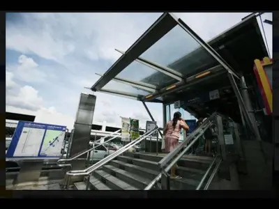 a woman walking up the stairs at a bus stop at Thailand Taxi Apartment Hostel in Thung Si Kan