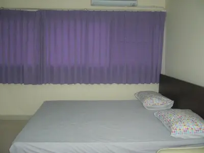 a bed with two pillows in front of a purple window at Chan Kim Don Mueang Guest House Triple room in Thung Si Kan