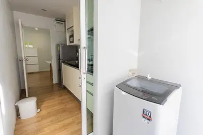 a room with a refrigerator and a kitchen with a hallway at United Residence Ekamai Bangkok in Bangkok
