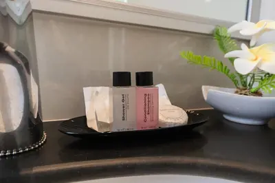 a bathroom counter with two products on a plate next to a sink at United Residence Ekamai Bangkok in Bangkok