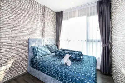 a teddy bear sitting on a bed in a bedroom at The Base Park East - Bangkok Sukhumvit 77 in Bangkok