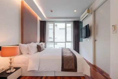 a bedroom with a white bed and a television at Beverly 33 by Aspira in Bangkok