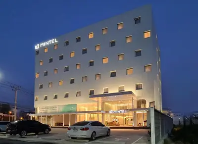 a hotel with two cars parked in a parking lot at Mintel Huamark in Bangkok