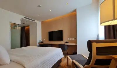 a bedroom with a bed and a desk with a television at Mintel Huamark in Bangkok
