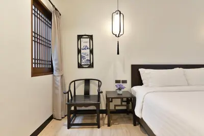 a bedroom with a bed and a chair and a window at Oldthaiheng Hotel in Bangkok
