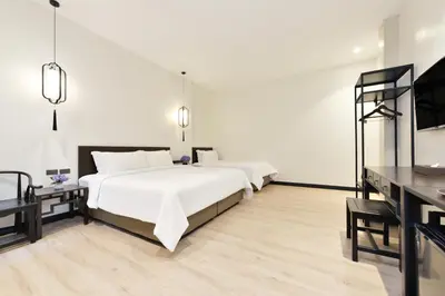 two beds in a room with white walls and wooden floors at Oldthaiheng Hotel in Bangkok
