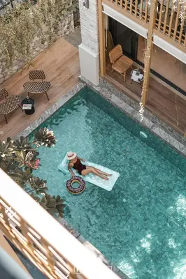 a woman is laying on a raft in a swimming pool at SHAN Villas Sukhumvit ฌานวิลล่า สุขุมวิท in Bangkok