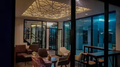 a lobby with chairs and a table and windows at Plearnwan Deluxe Mansion in Bangkok