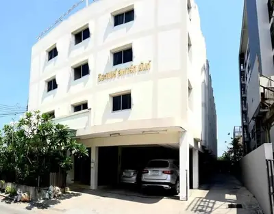 a white building with a car parked in a garage at Jirapong apartment in Bangkok