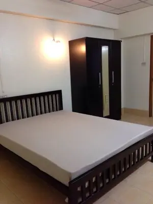 a large bed in a room with a black cabinet at Jirapong apartment in Bangkok