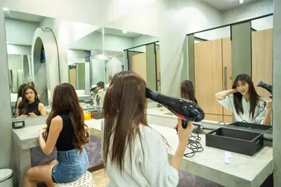 a woman blow drying her hair in front of a mirror at Third Rock Hostel in Bangkok