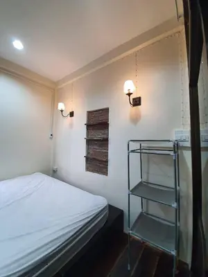 a bedroom with a bed and two lights and a shelf at บ้านอรุณHome in Bangkok