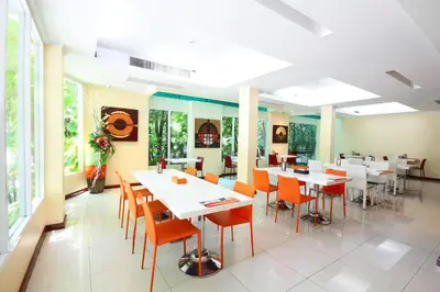 a dining room with white tables and orange chairs at Calypzo Bangkok in Bangkok