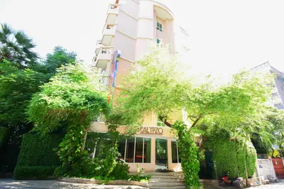 a tall white building with trees in front of it at Calypzo Bangkok in Bangkok
