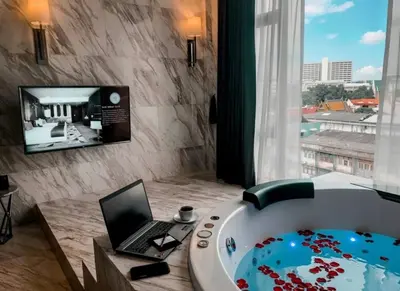 a bathroom with a tub with a laptop and a television at Ayathorn Bangkok in Bangkok