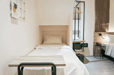 a small bed in a room with white walls at HOMITEL Bangkok in Bangkok