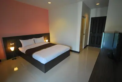 a bedroom with a bed and two lamps and a television at Baan Mina in Bangkok