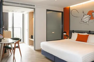 a bedroom with a bed and a table and a desk at The Quart Ruamrudee by UHG in Bangkok