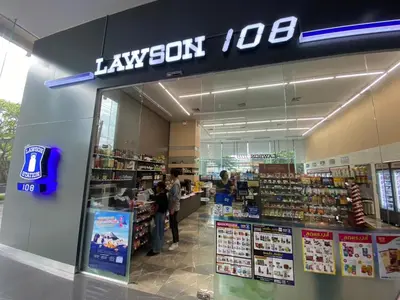 a lawson store with people standing in the aisle at The Quarter Onnut by UHG in Bangkok