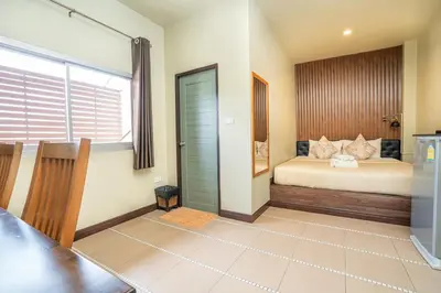 a bedroom with a bed and a table in it at The Palm Hotel in Salaya