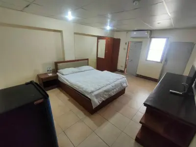 a bedroom with a bed and a desk and a window at PRL Place in Bangkok