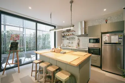 a kitchen with a large island with bar stools at humble abode Bangkok Vacation Home in Bangkok