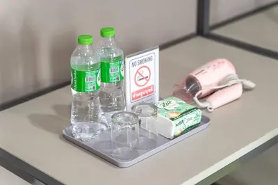 a shelf with bottles and glasses on a table at Sabai Residence @Bangyai in Nonthaburi