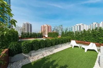 a garden with two white chairs and green grass at iCheck inn Residences Sathorn in Bangkok